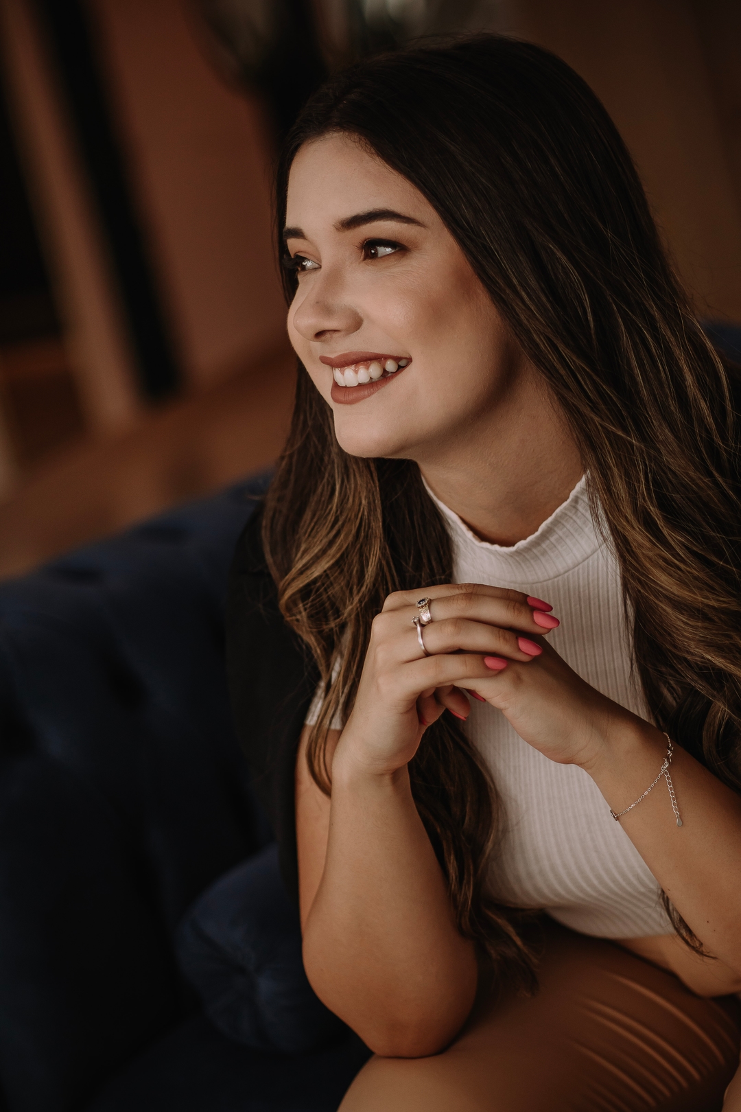 Psicóloga Kamila da Silveira. Uma mulher de cabelos longos que está sentada em uma poltrona azul e sorrindo.